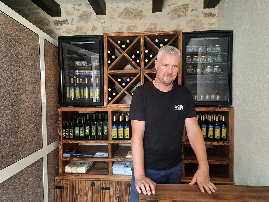 Il pescatore Krsto Ivoš con dietro l’olio d’oliva e altre casette di produzione familiare - Foto G. Vale Il pescatore Krsto Ivoš con dietro l’olio d’oliva e altre casette di produzione familiare - Foto G. Vale